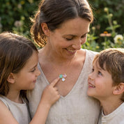 Mother wearing a custom three stone birthstone necklace while smiling with her children, a sentimental jewelry gift for moms.