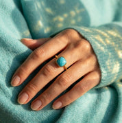 Model wearing a natural turquoise cushion ring with an aqua sweater.