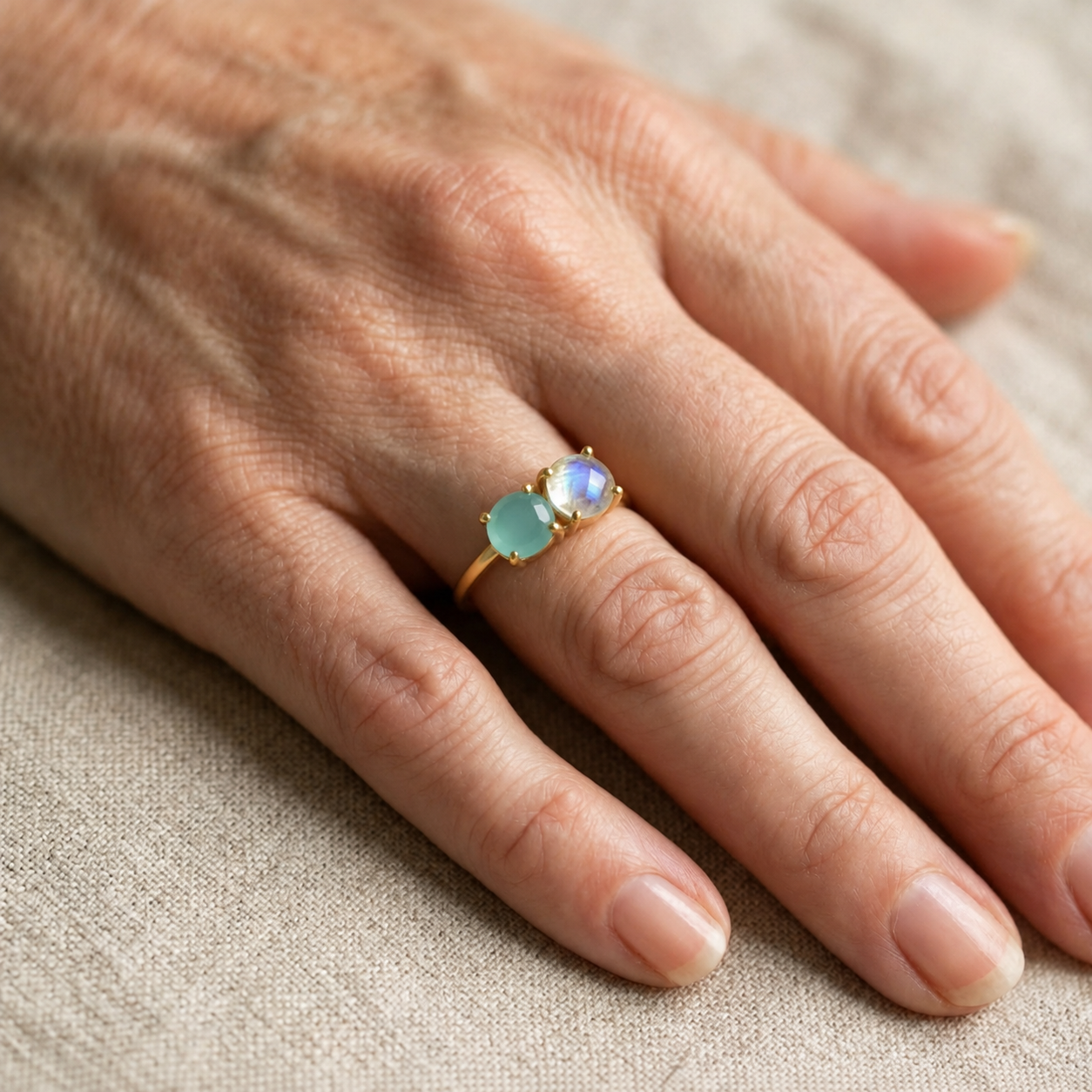 Woman wearing a personalized two birthstone ring with aqua and moonstone gemstones.