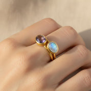 Close-up of stacked oval birthstone rings featuring February Birthstone Purple Amethyst and June Birthstone natural Rainbow Moonstone, thin gold bands with bezel-set stones, dainty stacking rings ideal for personalized birthstone jewelry and meaningful gifts