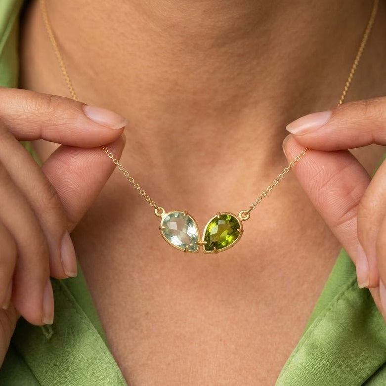 Custom two birthstone necklace with two faceted teardrop gemstones in yellow gold representing loved ones.