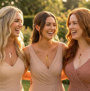 Three women wearing matching personalized bar necklaces with tiny birthstone charms, smiling together outdoors, showcasing custom engraved name necklaces as meaningful gifts for bridesmaids, best friends, or sister jewelry sets.