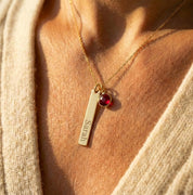 Personalized bar necklace close-up showing engraved name and tiny birthstone charm, minimalist jewelry gift for mom