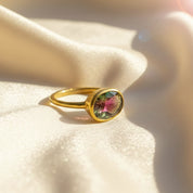 watermelon tourmaline oval bezel ring in 18k yellow gold vermeil resting on soft champagne satin fabric, multicolor pink-green tourmaline gemstone reflecting autumn tones, minimalist birthstone ring designed for October birthdays or anniversaries, ideal as a personalized gift for her such as mom, sister or best friend, stackable gemstone ring finished in sterling silver option, everyday dainty ring celebrating color and meaning.