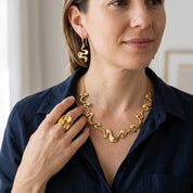 Woman wearing Gold Shifting Waves ring with matching necklace and earrings
