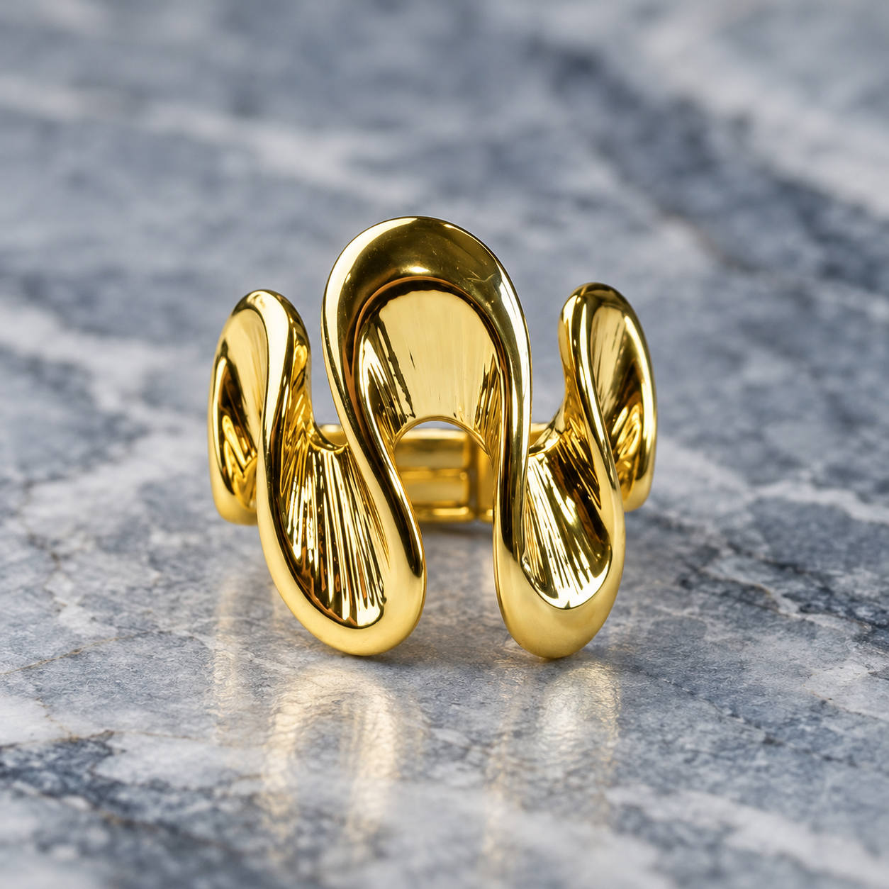 Gold Shifting Waves adjustable sculptural ring displayed on gray stone
