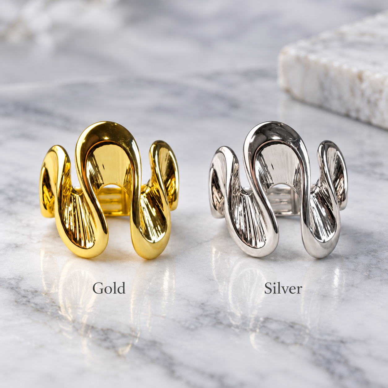Gold and Silver Shifting Waves adjustable rings displayed together on gray stone
