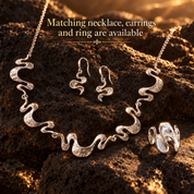 Matching Silver Shifting Waves necklace earrings and ring displayed on dark stone
