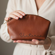 Custom engraved leather cosmetic bag in brown, personalized with name “Victoria.” Spacious design holds brushes, makeup, and essentials, making it the perfect bridesmaid gift, birthday present, or personalized travel pouch. A durable yet elegant custom cosmetic bag in full-grain leather, available in multiple colors with engraving options for initials, names, or handwriting.