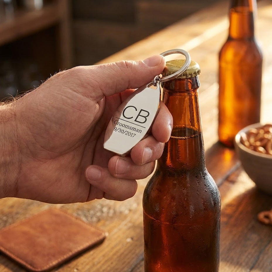 Custom engraved bottle opener keychain shown opening a beer bottle on wooden table. Personalized beer opener keychain designed as a functional keepsake gift for him.