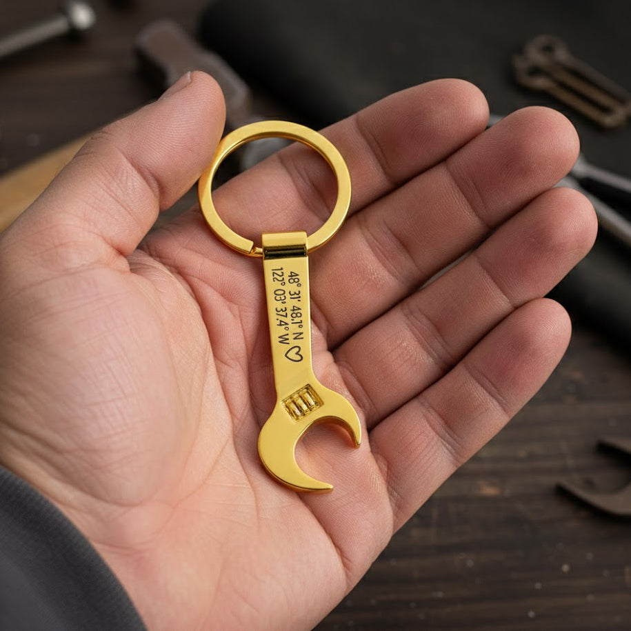 Personalized gold wrench keychain engraved with custom coordinates and heart, unique custom tool key ring for dad, grandpa, husband or boyfriend, great Father’s Day, anniversary or Christmas gift for handyman, mechanic or DIY lover held in man’s hand.
