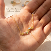 Close up of petite birthstone and initial charms in hand

