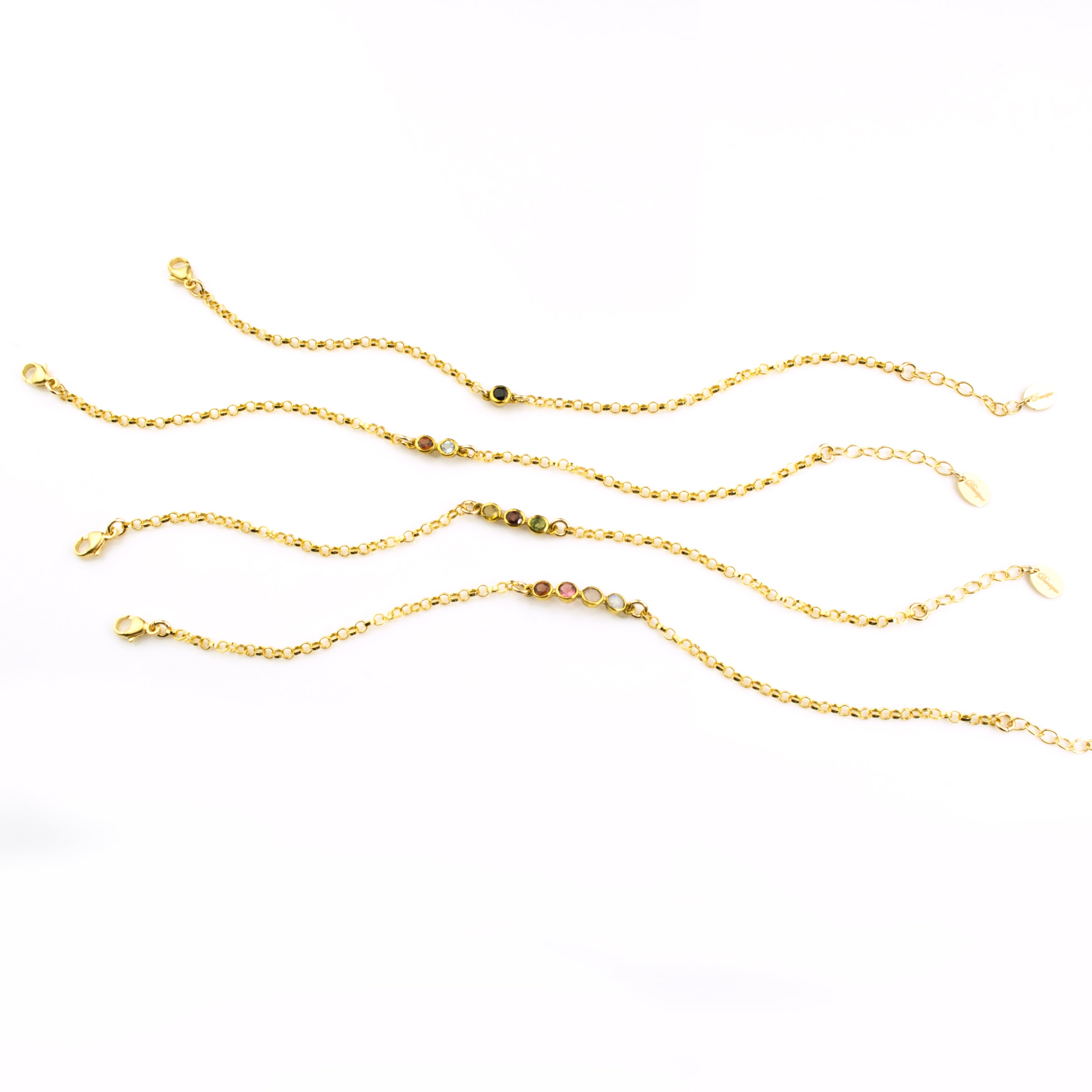 Four anklets that can be mixed and matched and layered! One anklet with black onyx gemstone. One anklet with garnet and clear gemstones. One anklet with peridot, garnet and peridot stones. One gold anklet with garnet, ruby, pink chalcedony and clear stones. 