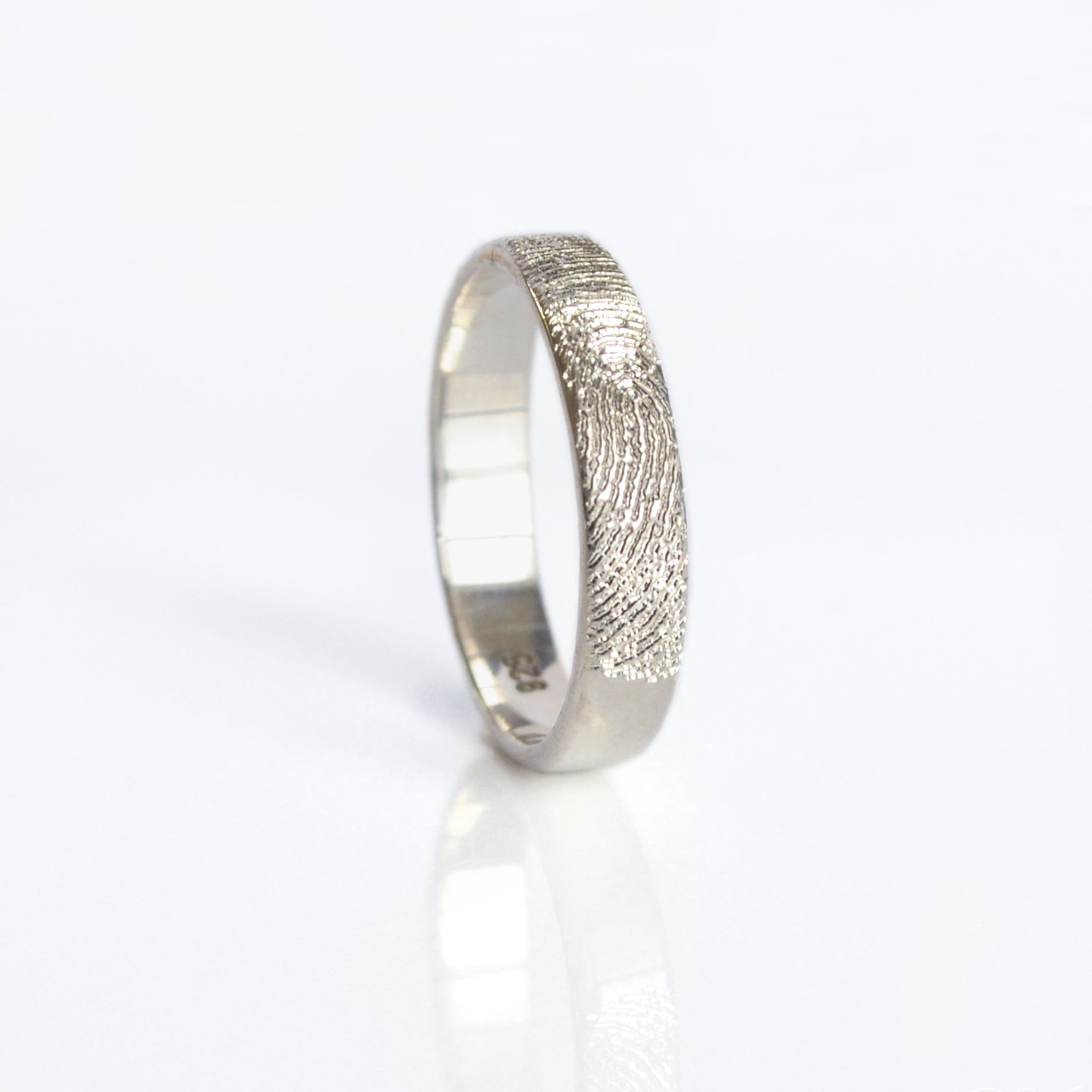 A sterling silver engraved fingerprint ring on its side. Custom fingerprint ring, thin handwriting band, sterling silver ring, gold engraved band, rose gold jewelry, unique names and dates, location coordinates, personal message, photo engraving option, versatile gift for him or her, US sizes 4-13, elegant design