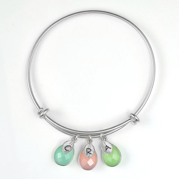 Single silver teardrop birthstone bangle with hand stamped leaf charms has aqua chalcedony, pink chalcedony and green chalcedony birthstones.