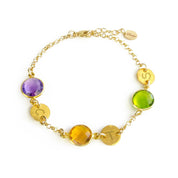 A gold bracelet featuring peridot and citrine and purple amethyst birthstones rests on a white background. Each birthstone is accompanied by a round disc charm with an initial hand stamped into it. August birthstone and September birthstone, green gemstone, purple gemstone, yellow gemstone, custom made personalized mother's bracelet with birthstones
