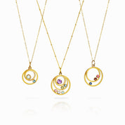 Three gold filled orbital necklace, first featuring two orbit pendants with moonstone and blue topaz. Middle necklace features a satellite chain with purple amethyst, peridot, blue topaz, pink chalcedony, moonstone and aqua chalcedony. Last necklace has garnet, ruby and kyanite birthstones
