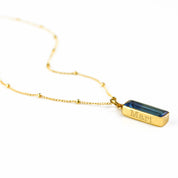 Single gold filled satellite chain with vertical september kyanite adira bar birthstone with secret message engraved in typewriter font. 