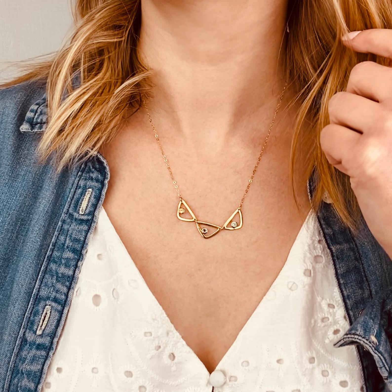 Model in white top is wearing a gold filled open triangle geometric necklace with citrine, purple amethyst and aqua chalcedony birthstones