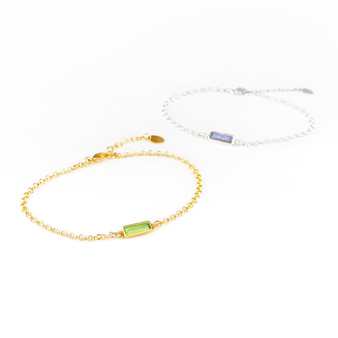 Two alternating gold filled and sterling silver chain adira bar bracelets featuring peridot and labradorite birthstones on white background
