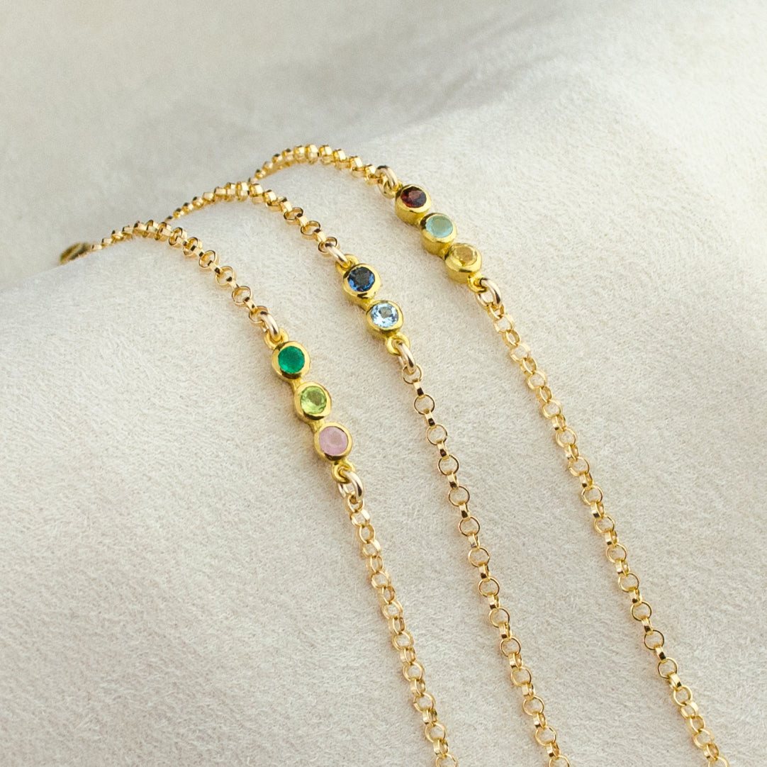 Trio of gold anklets. One gold anklet with 3 stones including garnet, aqua chalcedony and citrine. One gold anklet with November topaz and September sapphire. One gold anklet with May Emerald, August peridot and October Opal