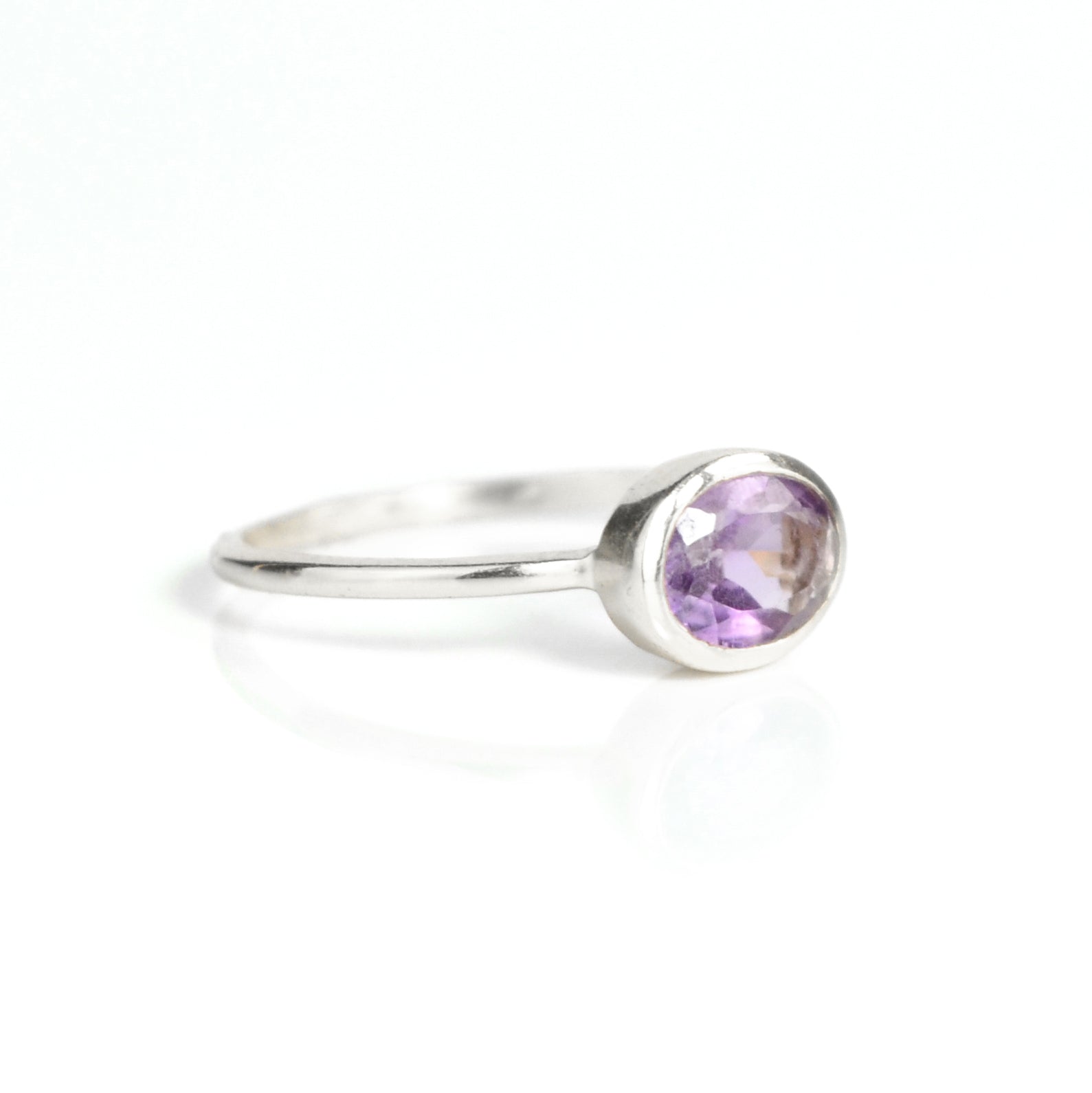 a sterling silver purple amethyst ring shown on white background. stackable! Stacking rings, bezel set, small oval, tiny oval, dainty oval, birthstone rings, sterling silver stamp, birthstone ring, birthstone jewelry, purple gemstone, purple birthstone, february birthstone, february gemstone