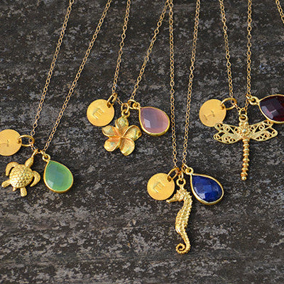 Custom angel wing necklaces with various birthstone colors and initial charms shown together, a thoughtful sympathy or remembrance jewelry collection for gifting.