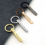 Collection of vertical bar keychains in black, silver, gold, and rose gold on a matte card, each etched with different phrases. Demonstrates color variety, deep engraving, and clean lines—ideal for monogram keyring, “drive safe I need you here” message, or matching groomsmen keychain set for weddings and bachelor party favors.