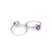 Back and front facing set of sterling silver diamond shape bezel set rings with purple amethyst birthstone. 