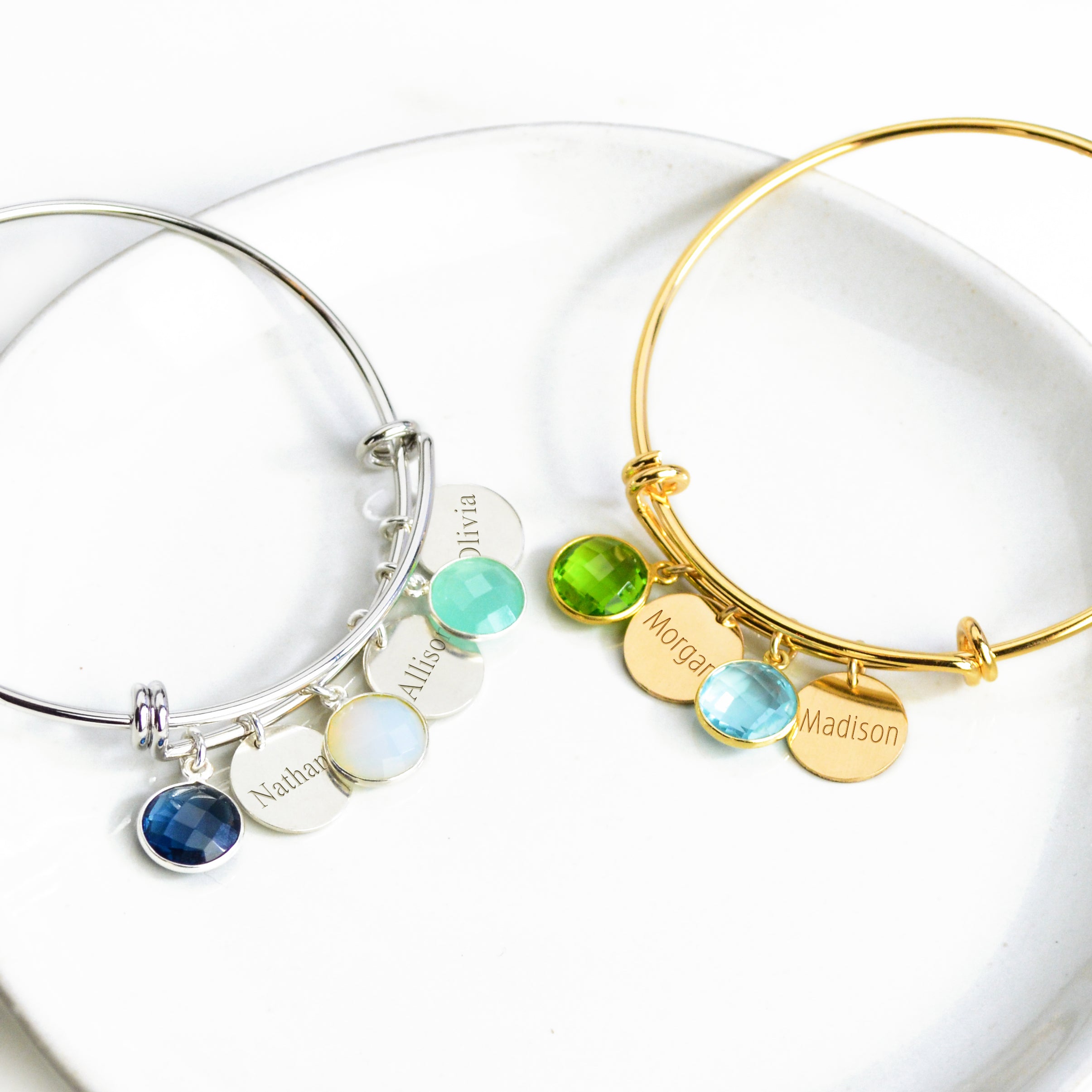 Sterling silver bangle bracelet with name tags in classic font and kyanite, moonston and aqua chalcedony. Single gold bangle bracelet with two name disks and peridot and blue quartz birthstones with names engraved in modern thin font