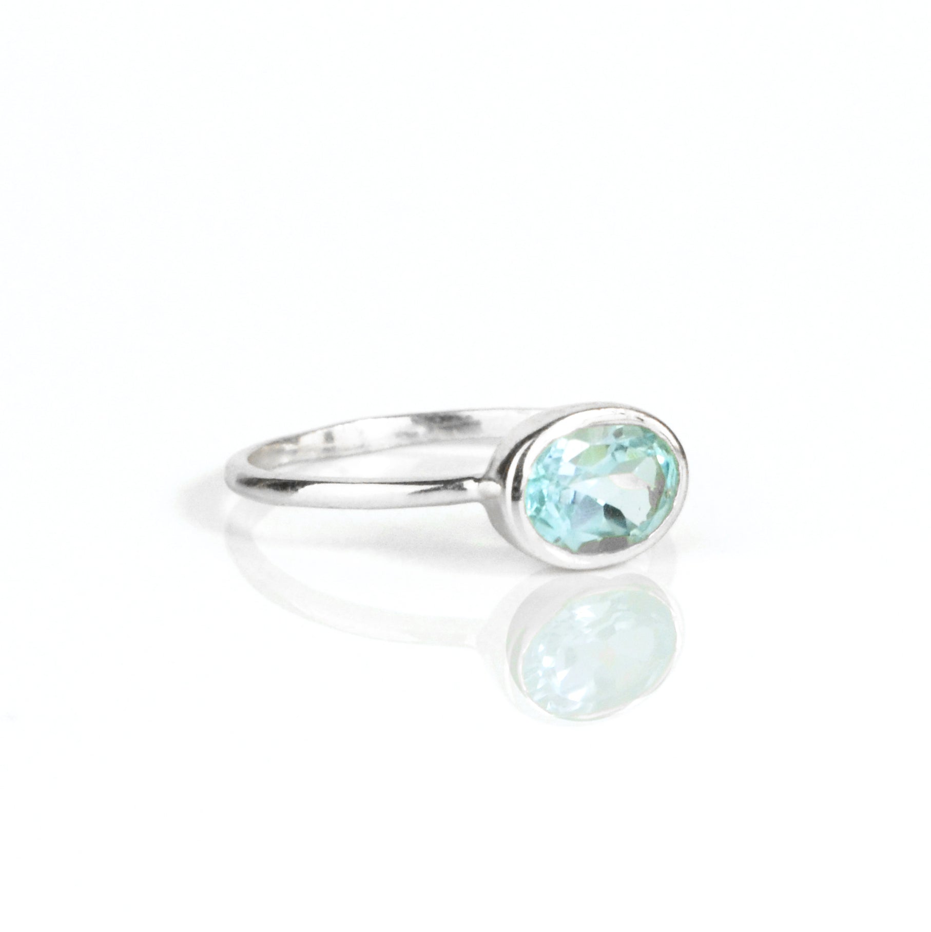 a sterling silver blue topaz ring shown on white background. stackable! Stacking rings, bezel set, small oval, tiny oval, dainty oval, birthstone rings, sterling silver stamp, birthstone ring, birthstone jewelry, blue gemstone, blue birthstone, december birthstone, december gemstone