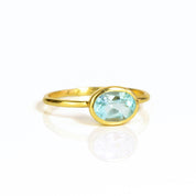 a gold blue topaz ring shown on white background. stackable! Stacking rings, bezel set, small oval, tiny oval, dainty oval, birthstone rings, sterling silver stamp, birthstone ring, birthstone jewelry, blue gemstone, blue birthstone, december birthstone, december gemstone
