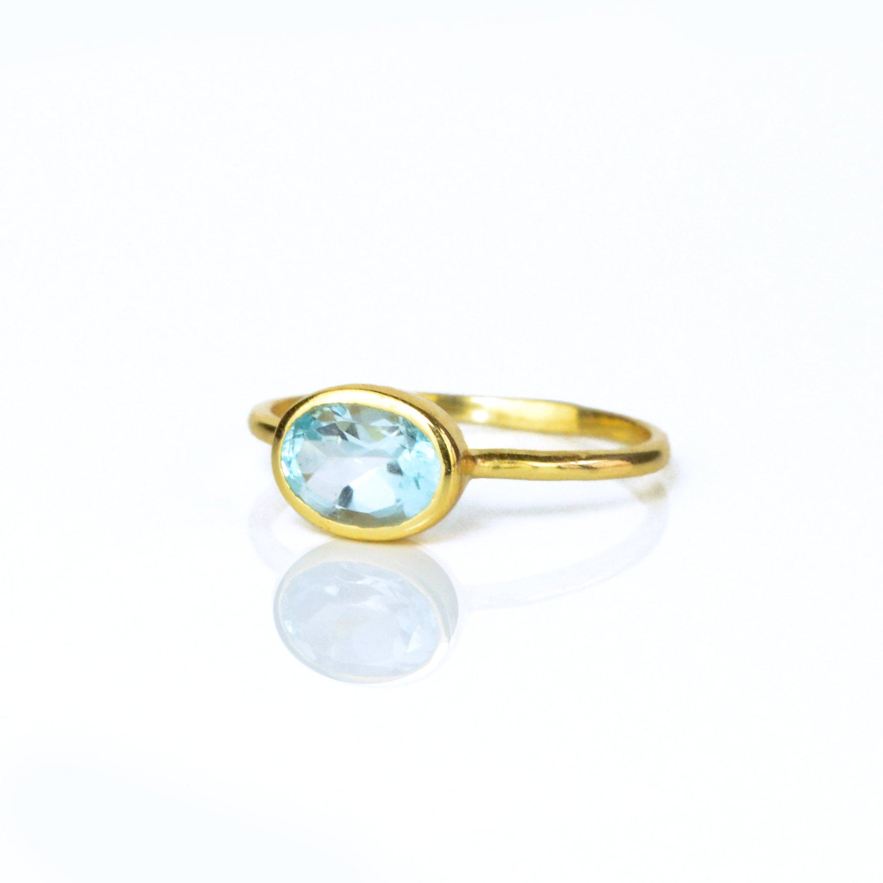 a gold blue topaz ring shown on white background. stackable! Stacking rings, bezel set, small oval, tiny oval, dainty oval, birthstone rings, sterling silver stamp, birthstone ring, birthstone jewelry, blue gemstone, blue birthstone, december birthstone, december gemstone
