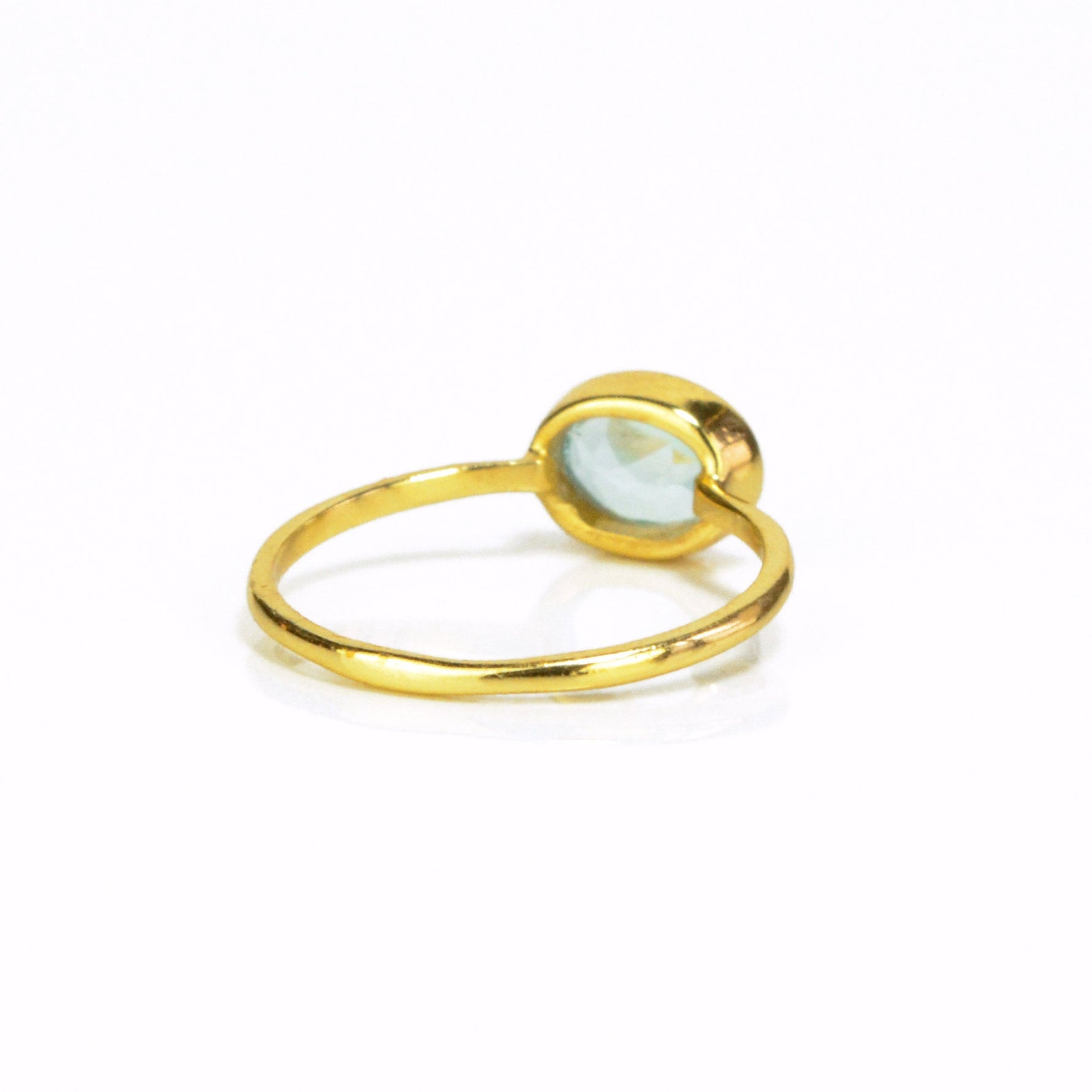 a rear view of the gold blue topaz ring shown on white background. stackable! Stacking rings, bezel set, small oval, tiny oval, dainty oval, birthstone rings, sterling silver stamp, birthstone ring, birthstone jewelry, blue gemstone, blue birthstone, december birthstone, december gemstone