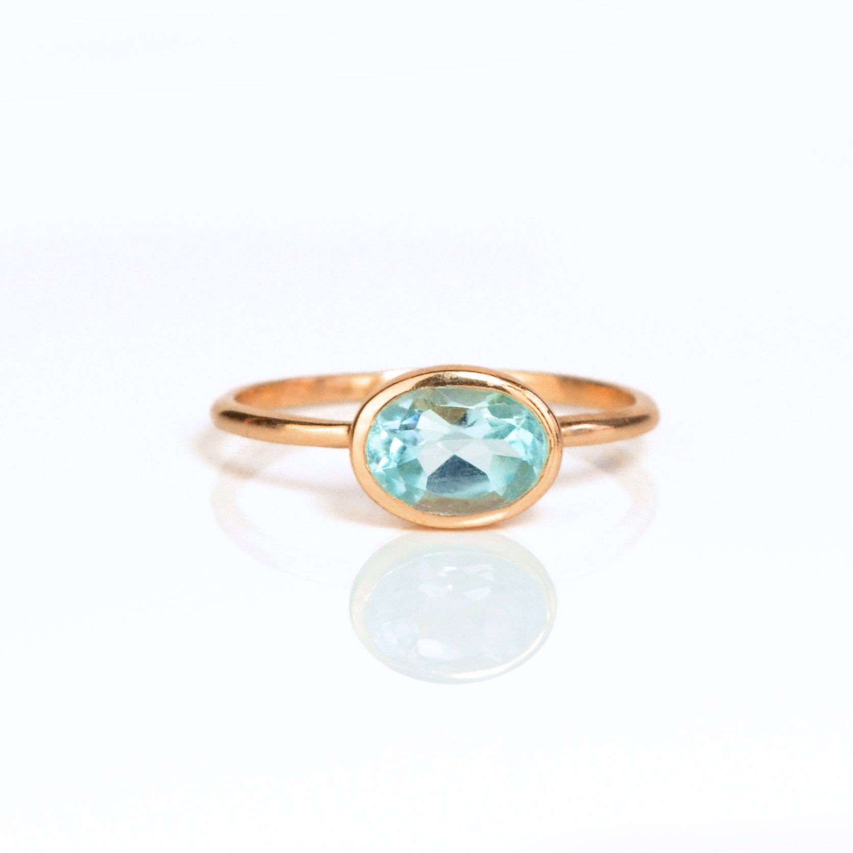 a rose gold blue topaz ring shown on white background. stackable! Stacking rings, bezel set, small oval, tiny oval, dainty oval, birthstone rings, sterling silver stamp, birthstone ring, birthstone jewelry, blue gemstone, blue birthstone, december birthstone, december gemstone