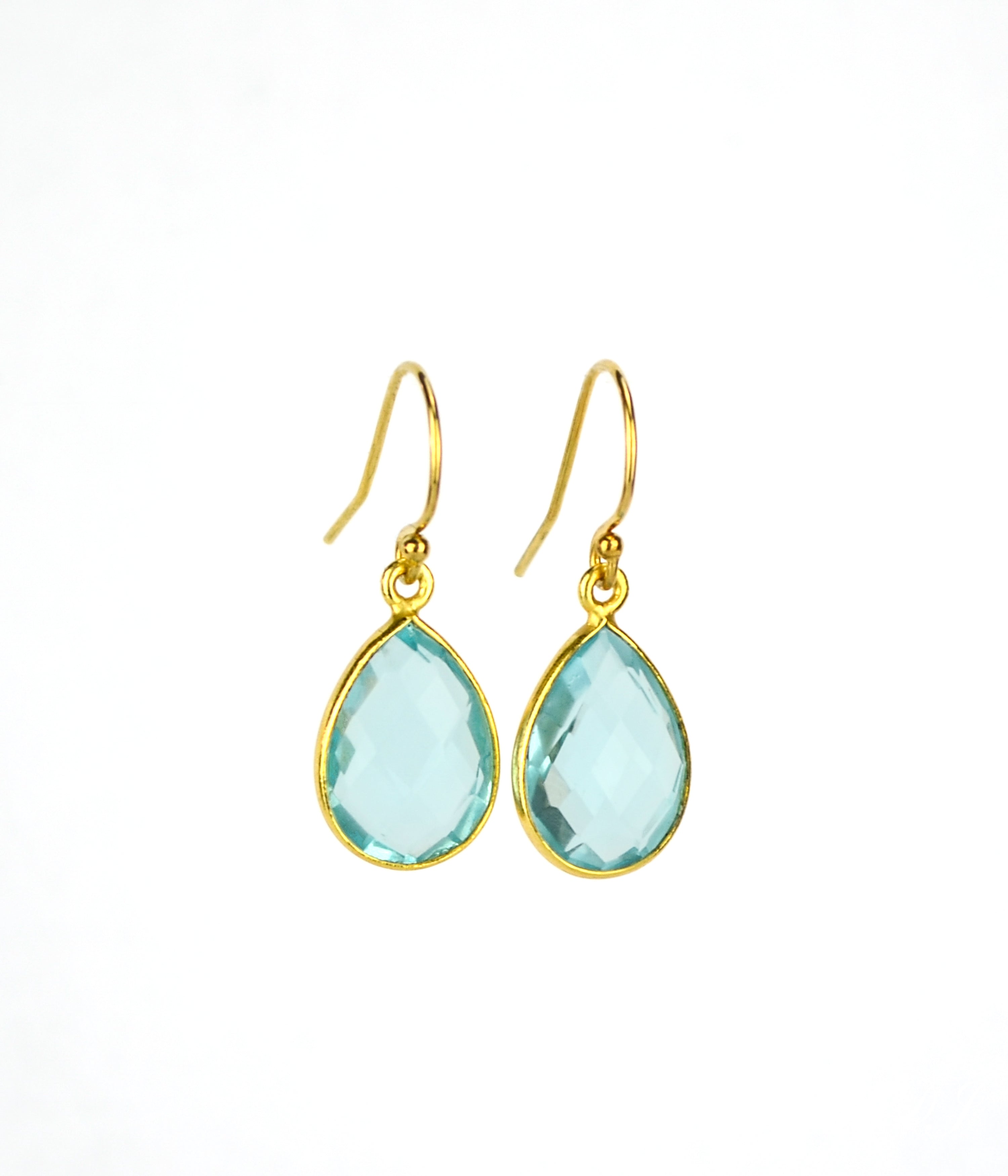 Small gold filled teardrop blue topaz birthstone earrings on a white background. Blue topaz gemstone, december birthstone. 