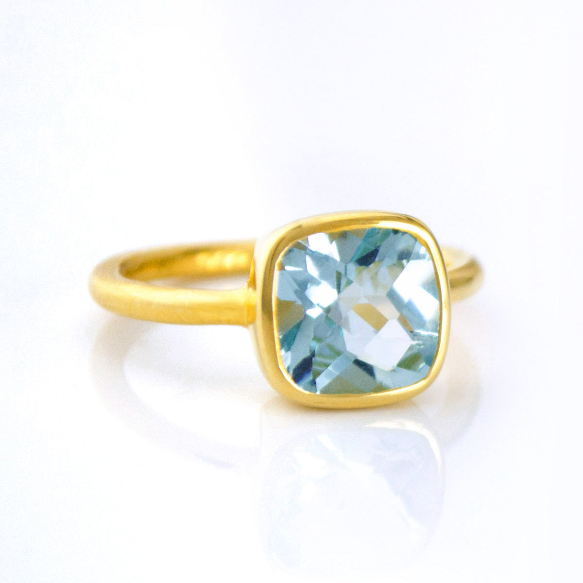 blue topaz gold plated cushion square stacking ring on white background. december birthday, december gemstone
