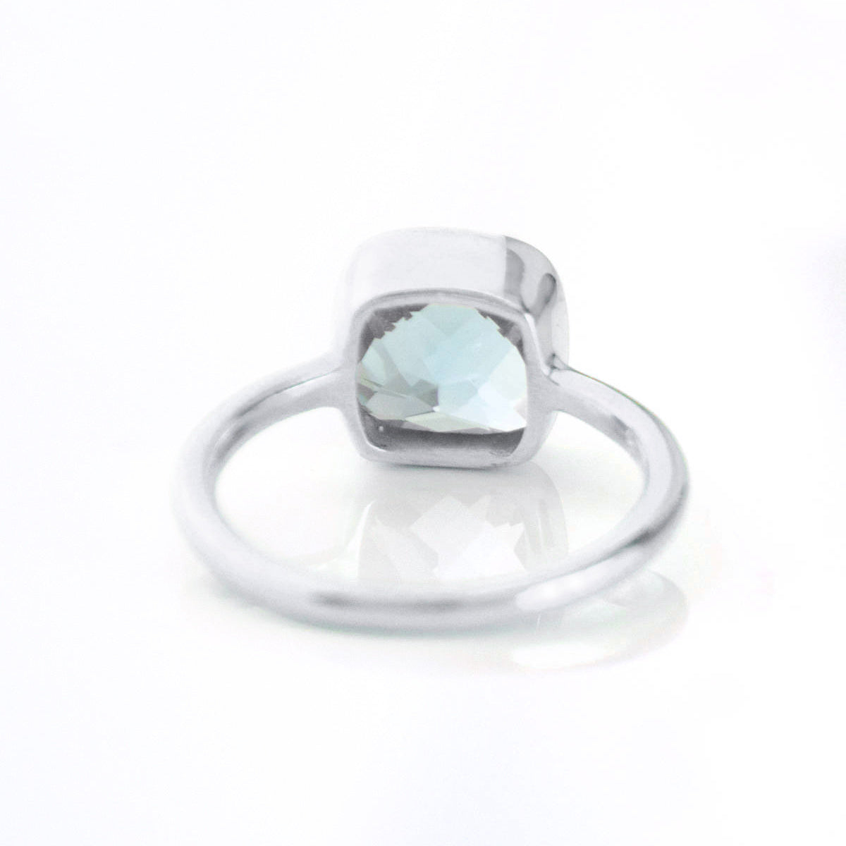 sterling silver blue topaz december birthstone ring facing away december gemstone, cushion cut on white background