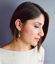 Model is wearing gold cascade earrings with purple amethyst, green onyx and moonstone.