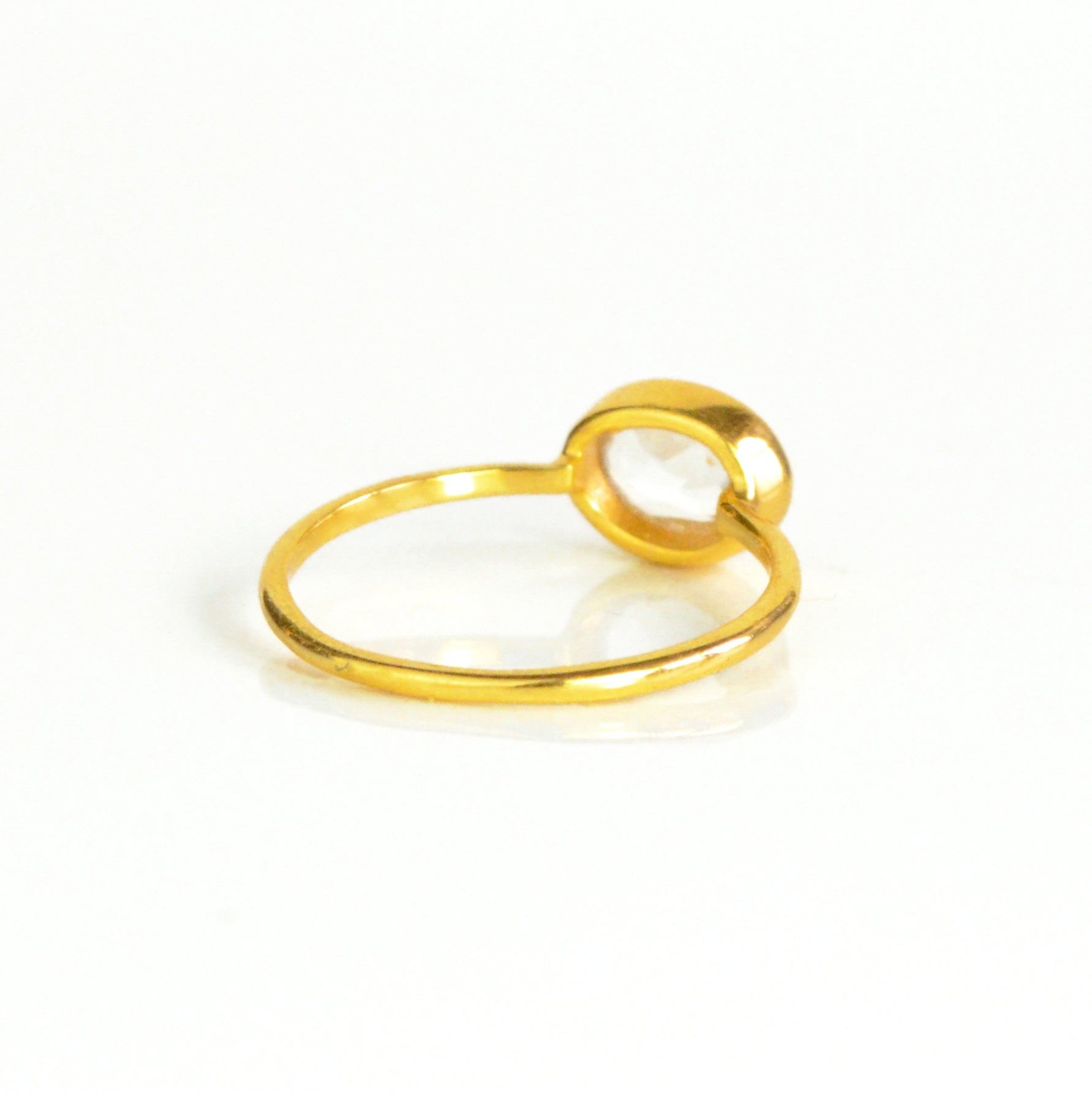 rear view of a gold clear quartz ring shown on white background. stackable. Stacking rings, bezel set, small oval, dainty oval, birthstone rings, sterling silver stamp, birthstone ring, birthstone jewelry, clear gemstone, clear quartz birthstone, april birthstone, april gemstone,  stack set, stacking rings, christmas gift, birthstone ring, mother's day gift for her, gift for mom, gift for fiance, gift for girlfriend, wedding jewelry, bridesmaid jewelry, anniversary jewelry, anniversary gift, birthday gift