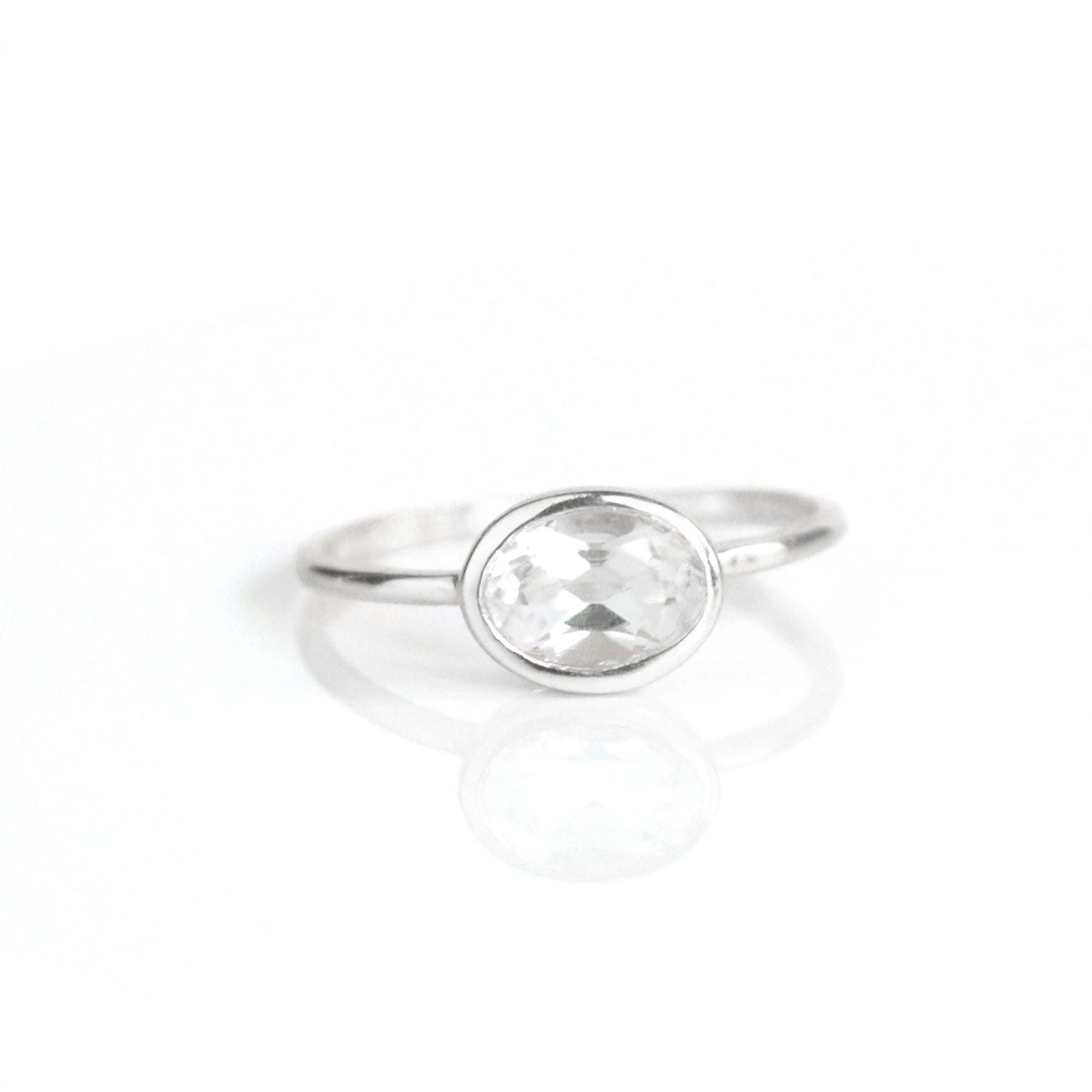 a sterling silver clear quartz ring shown on white background. stackable! Stacking rings, bezel set, small oval, tiny oval, dainty oval, birthstone rings, sterling silver stamp, birthstone ring, birthstone jewelry, clear gemstone, clear quartz birthstone, april birthstone, april gemstone