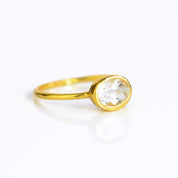 a gold clear quartz ring shown on white background. stackable. Stacking rings, bezel set, small oval, dainty oval, birthstone rings, sterling silver stamp, birthstone ring, birthstone jewelry, clear gemstone, clear quartz birthstone, april birthstone, april gemstone,  stack set, stacking rings, christmas gift, birthstone ring, mother's day gift for her, gift for mom, gift for fiance, gift for girlfriend, wedding jewelry, bridesmaid jewelry, anniversary jewelry, anniversary gift, birthday gift