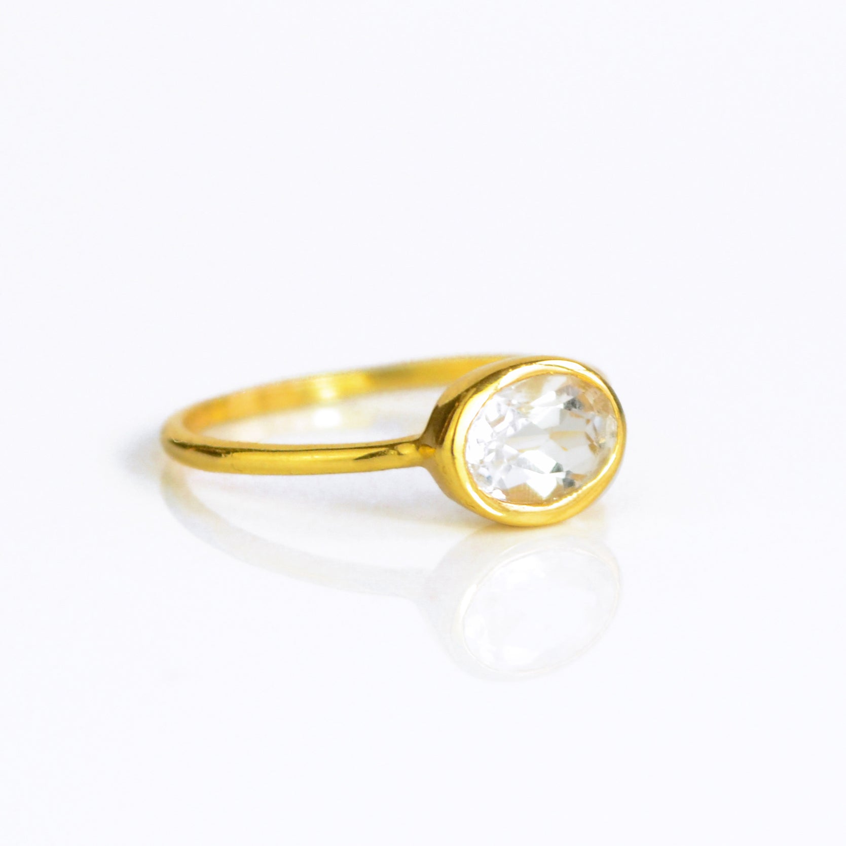 a gold clear quartz ring shown on white background. stackable! Stacking rings, bezel set, small oval, tiny oval, dainty oval, birthstone rings, sterling silver stamp, birthstone ring, birthstone jewelry, clear gemstone, clear quartz birthstone, april birthstone, april gemstone