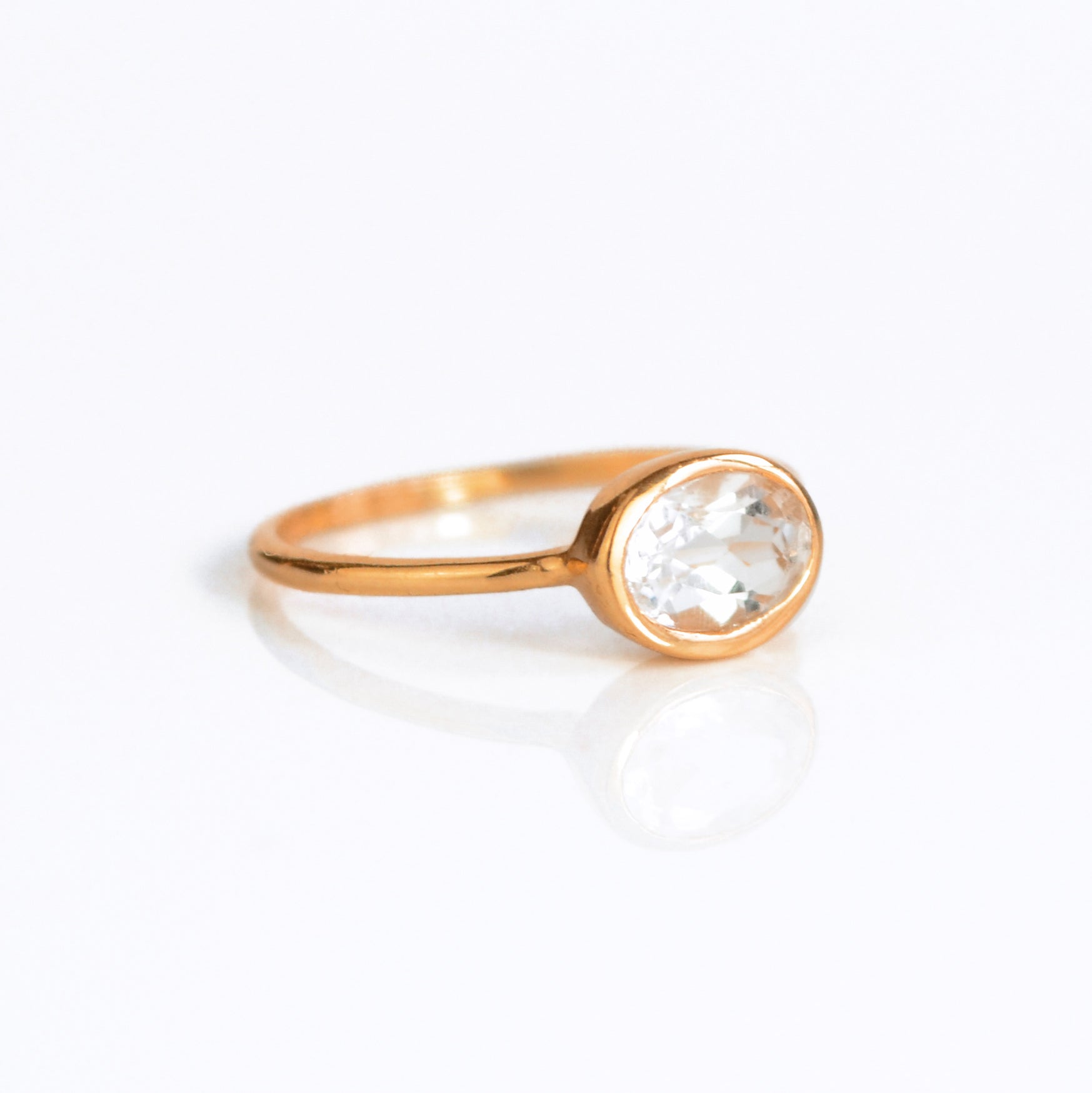 a rose gold clear quartz ring shown on white background. stackable! Stacking rings, bezel set, small oval, tiny oval, dainty oval, birthstone rings, sterling silver stamp, birthstone ring, birthstone jewelry, clear gemstone, clear quartz birthstone, april birthstone, april gemstone