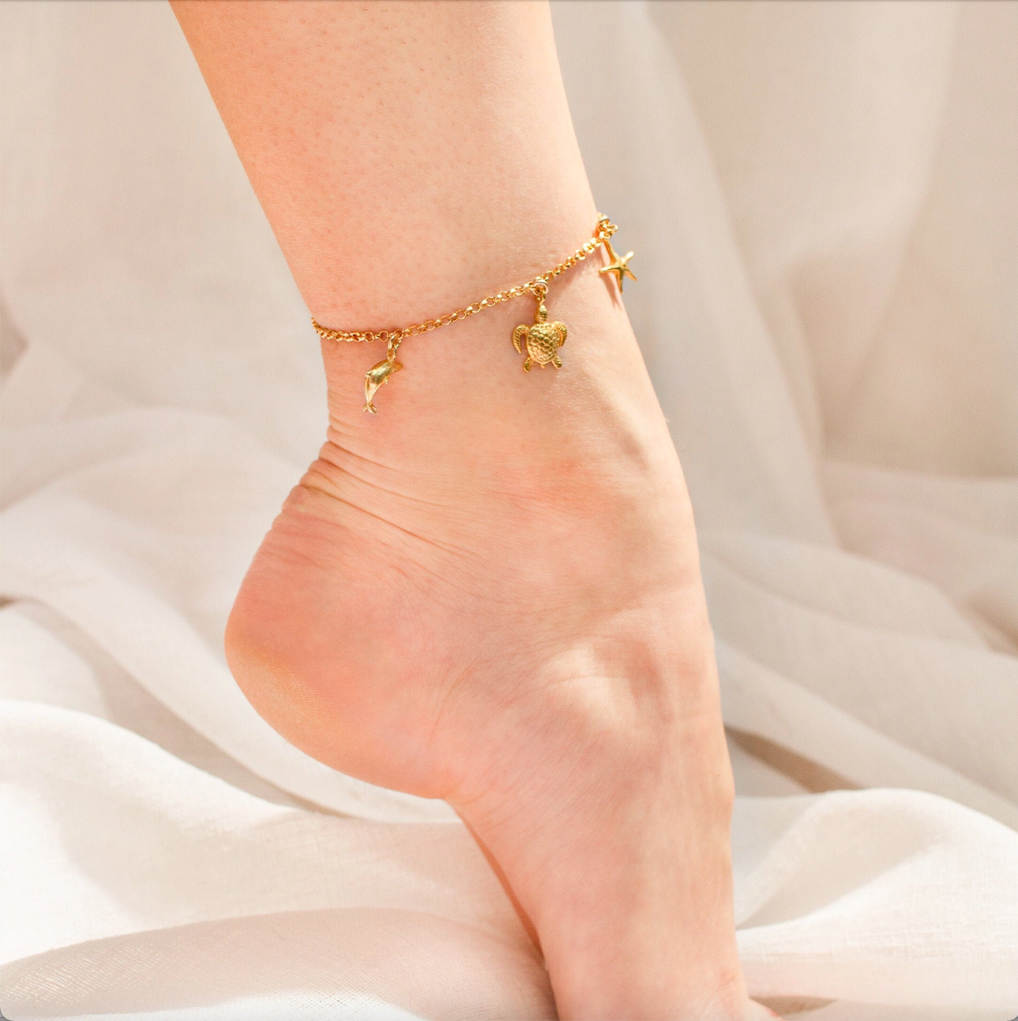 Model is wearing the gold filled charm anklet with dolphin, turtle and starfish charms. Great gift for any beach lover!