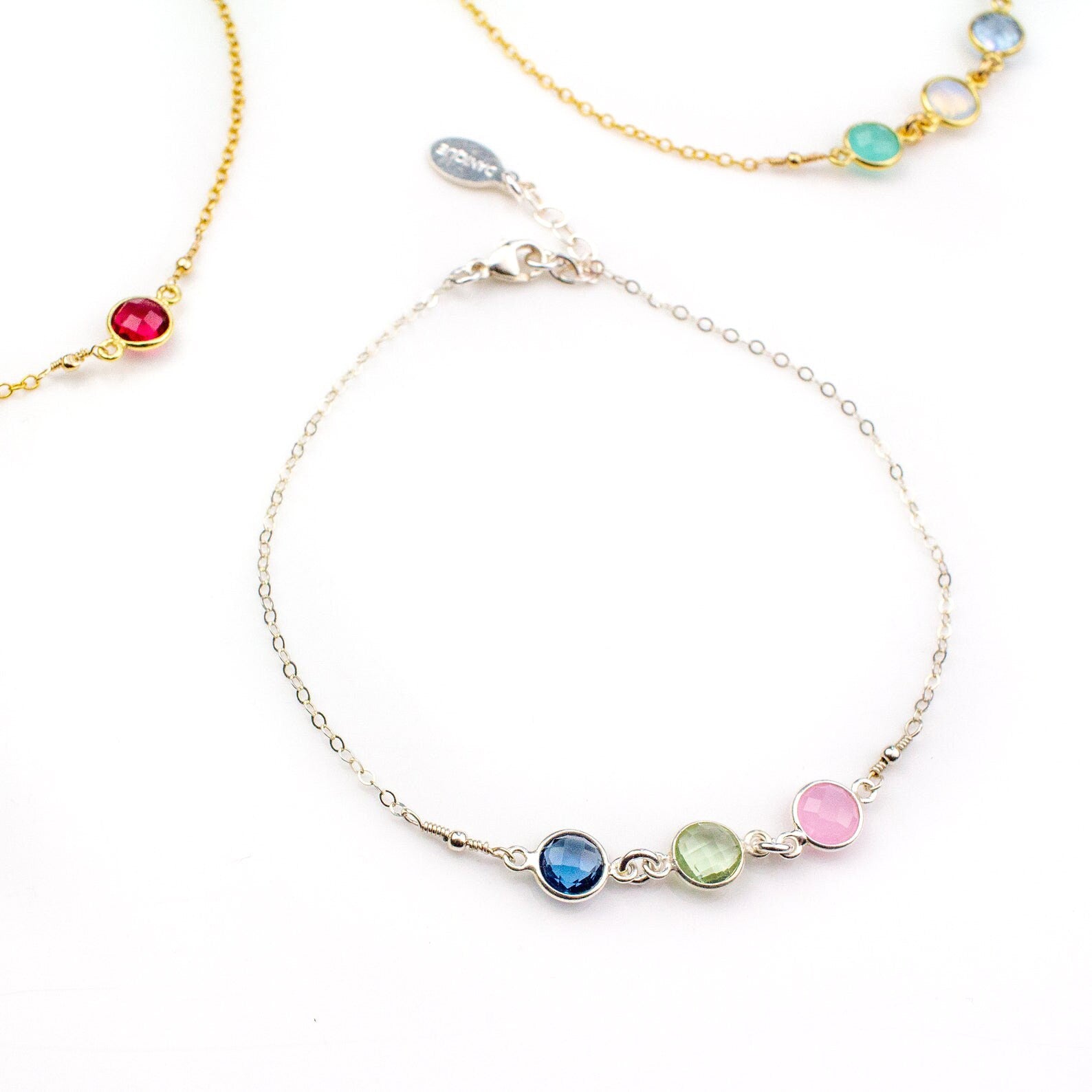 Close up of trio of anklets including silver with kyanite, green amethyst and pink chalcedony.
