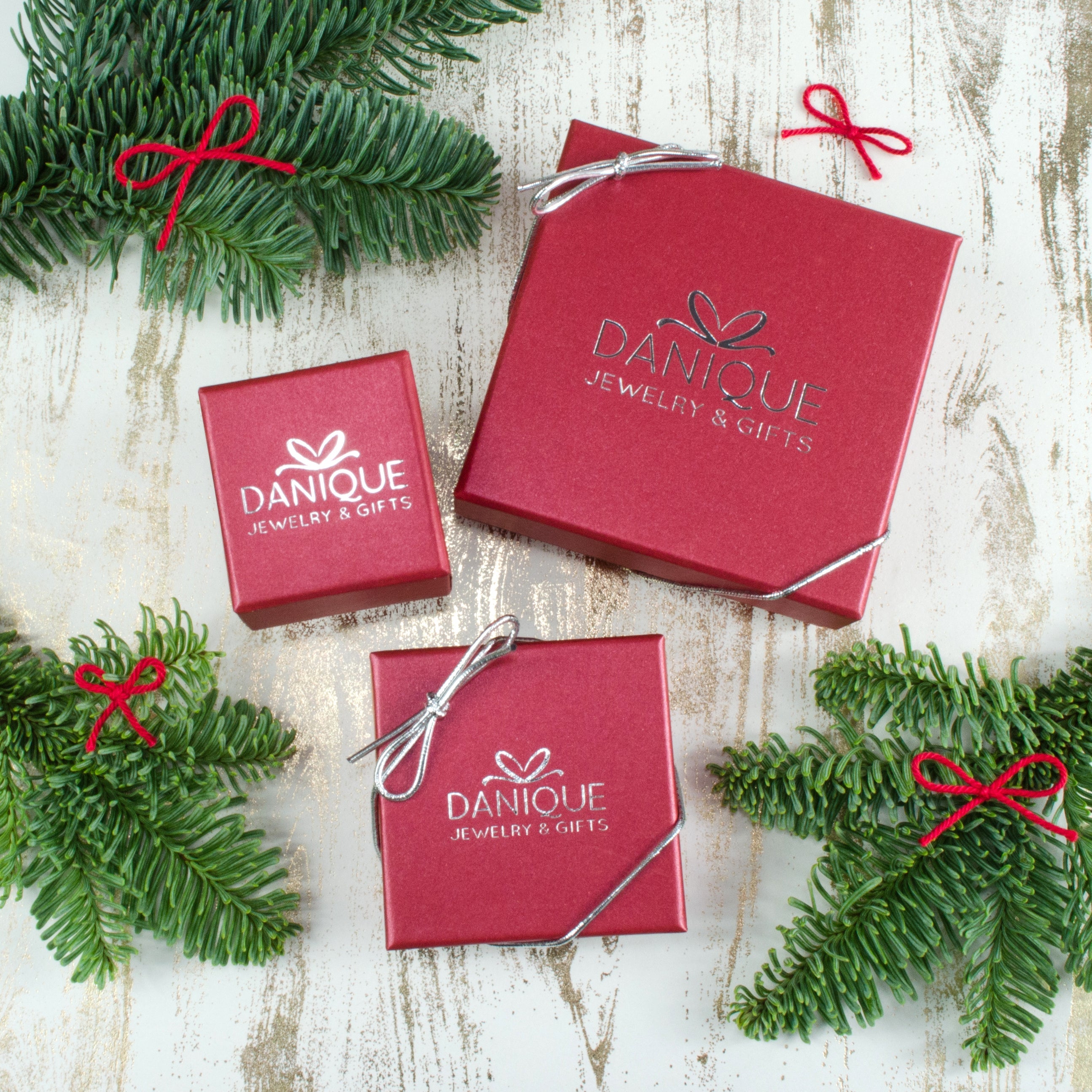 3 red danique jewelry boxes against a birch white background with evergreen pines peeking out the sides of the frame. Each Danique Jewelry gift is carefully packaged in red boxes and finished with a silver stretchy bow. Christmas gift, Mother's Day gift, birthday gift, last minute gift, express shipping, fast delivery, fast shipping, handmade, custom, personalized, mother's jewelry, grandma jewelry, best friend jewelry, sister jewelry, mother in law necklace, MIL jewelry, gold, silver, rose gold, oxidized