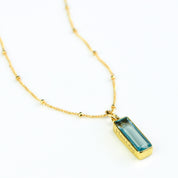 Single gold filled satellite chain with vertical sky blue gemstone with secret message engraved december birthstone adira bar necklace on white background