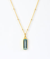 Single gold filled satellite chain with vertical sky blue gemstone december birthstone adira bar necklace on white background