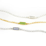 Three alternating silver and gold chain adira bar bracelets featuring, moonstone, peridot and labradorite birthstones on white background